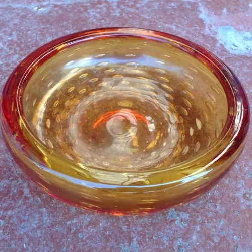 shallow orange glass bowl with air bubbles