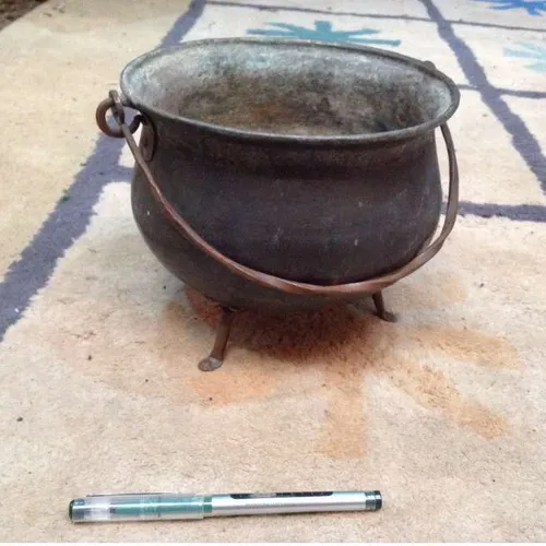 well-worn metal caldron with handle