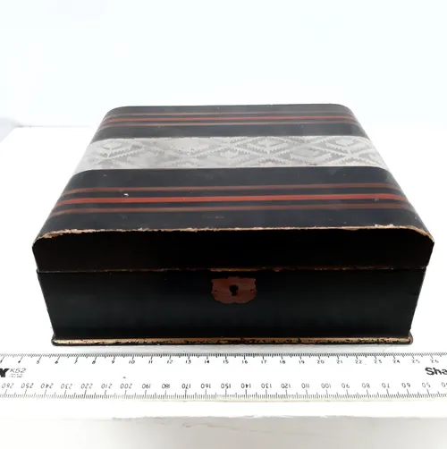 Square black box with red/gold stripes and silver design