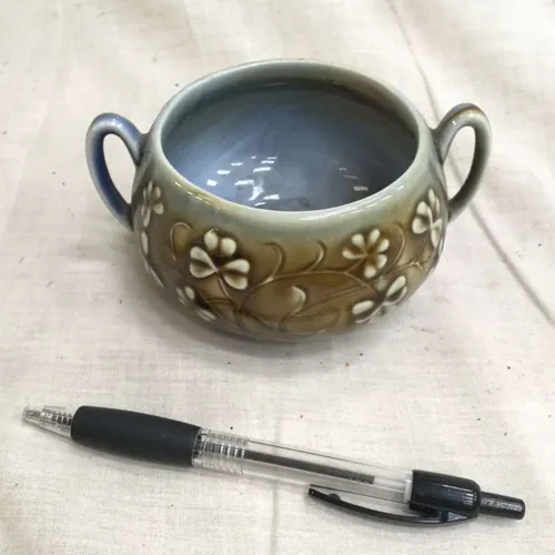 Small brown/blue ceramic dish with two handles and raised floral details