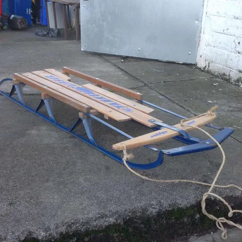Wooden sledge with metal runners and rope handle