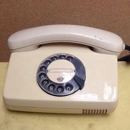 beige and black corded rotary dial telephone