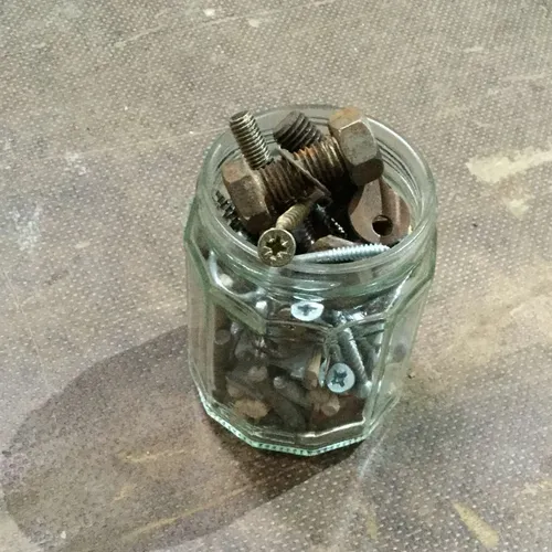Small glass jar of screws and nails
