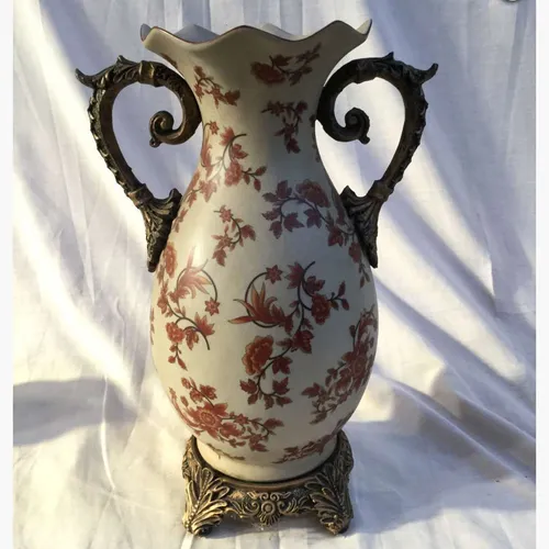 Ceramic vase with flowers and gold handles and base
