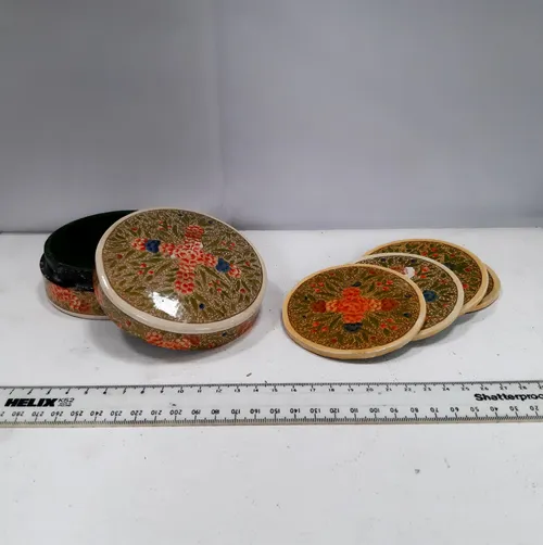 Round box of coasters with pink flower and green leaf design 