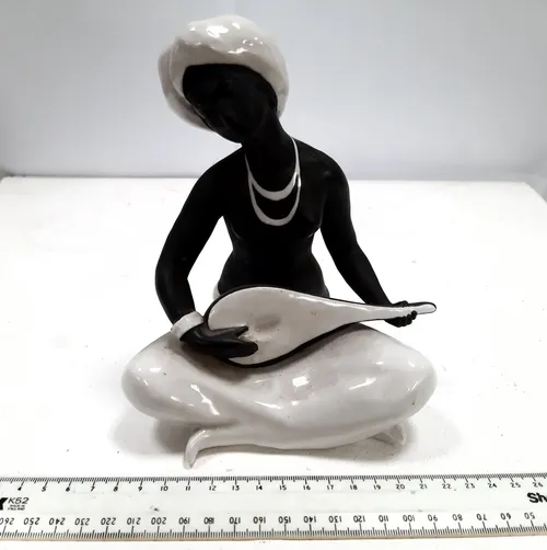 Figurine of woman sitting cross legged with guitar