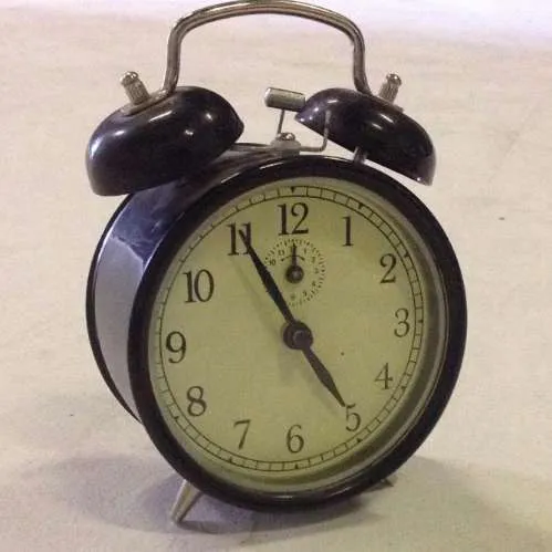 black metal analogue twin bell alarm clock with pale yellow/cream face