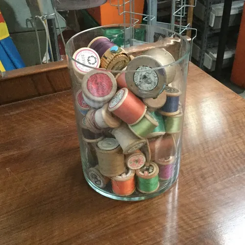 Glass Jar Full of Various Spools of Thread