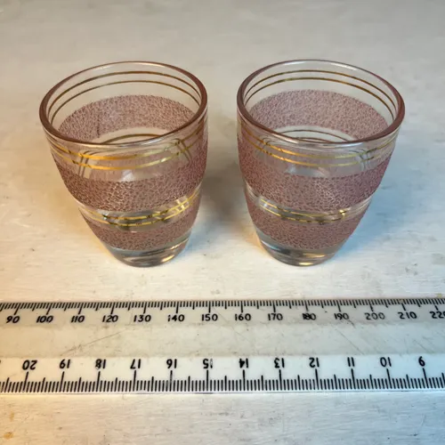 Pair of shot glasses with pink sugar texture and gold bands