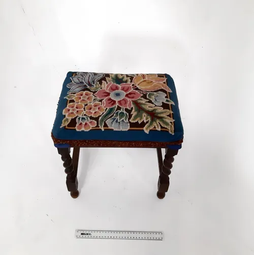 Small dark wood foot stool with blue cushion and colourful embroidered flower design