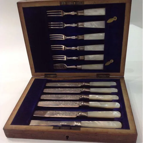 set of knives and forks with mother of pearl handles and decorative etching in wood case
