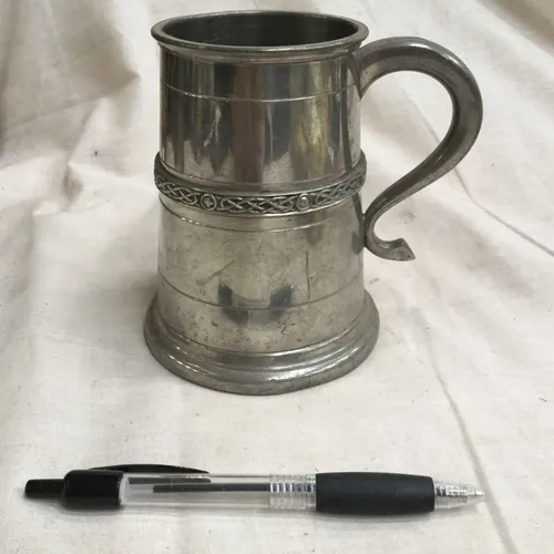 Polished metal tankard with Celtic band and S shaped handle