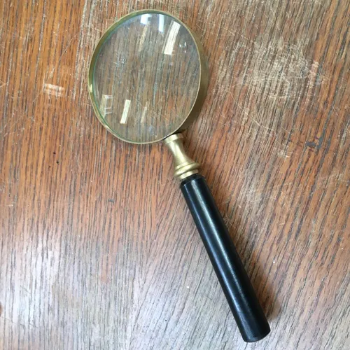 Period magnifying glass with brass frame and black handle