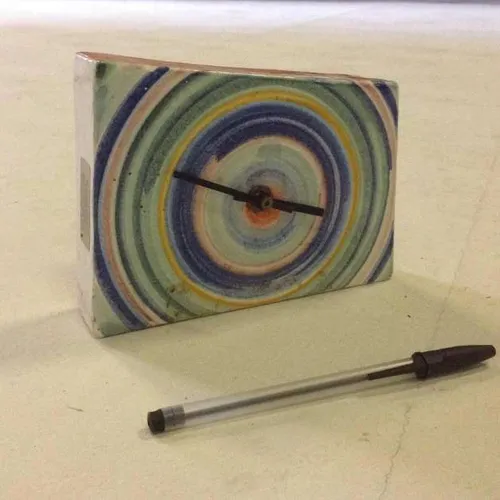 ceramic analogue shelf mantle clock with multi coloured face design and no face cover