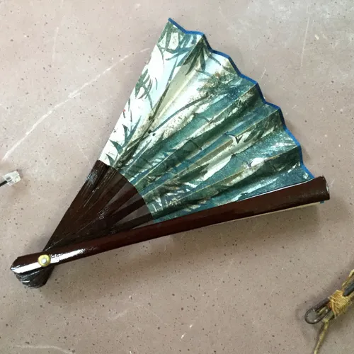 Small dark wood hand fan with jungle leaf print design