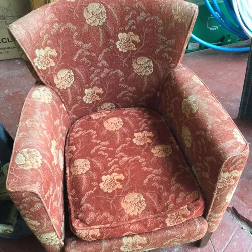 arm chair with faded red fabric and floral pattern