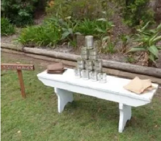 Tin Can Alley � White bench with beanbags & tins.